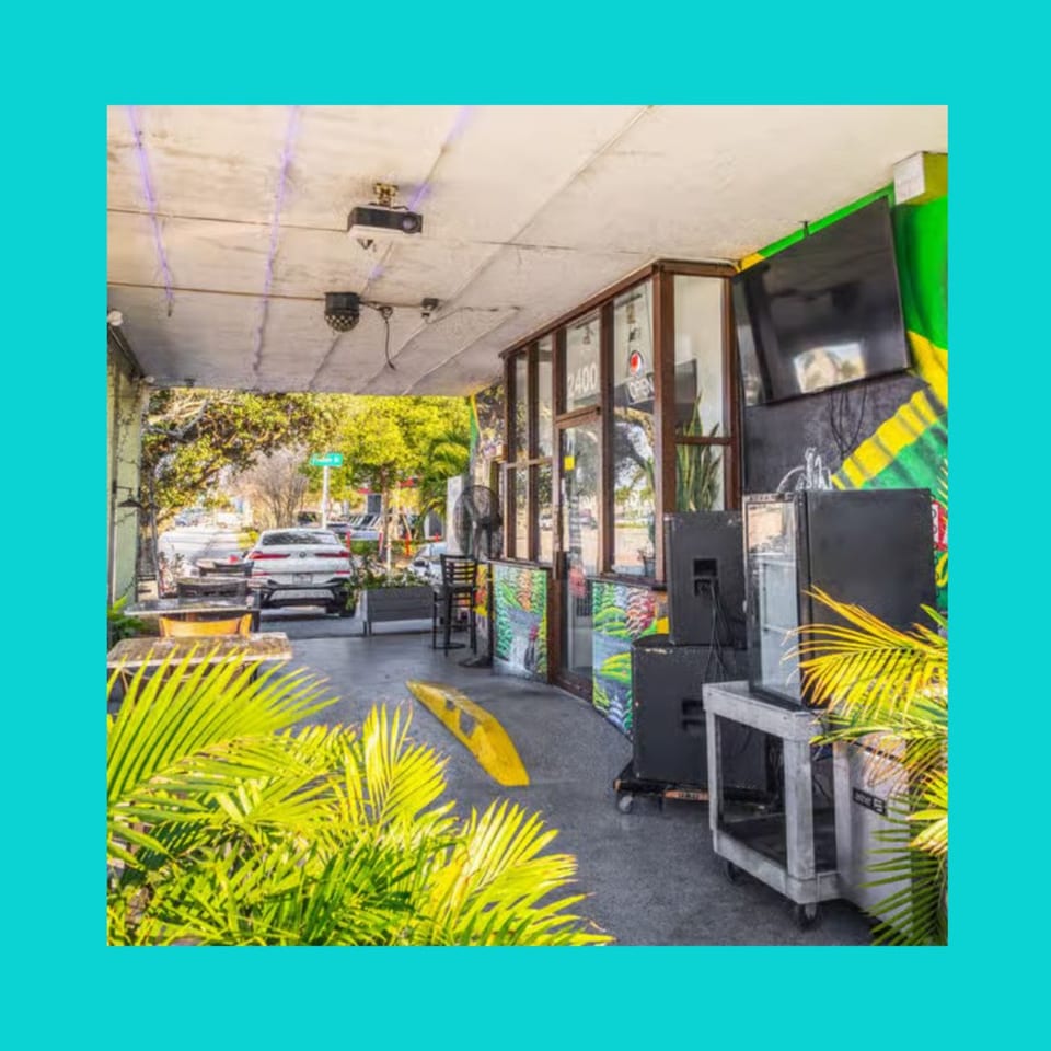 Outdoor patio of Mr Mack's Jamaican restaurant with tables, chairs, and lush green plants.