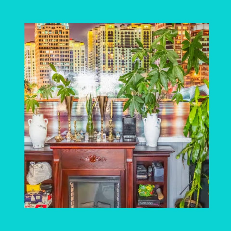 A decorative fireplace with plants and golden candle holders, set against a city skyline mural.