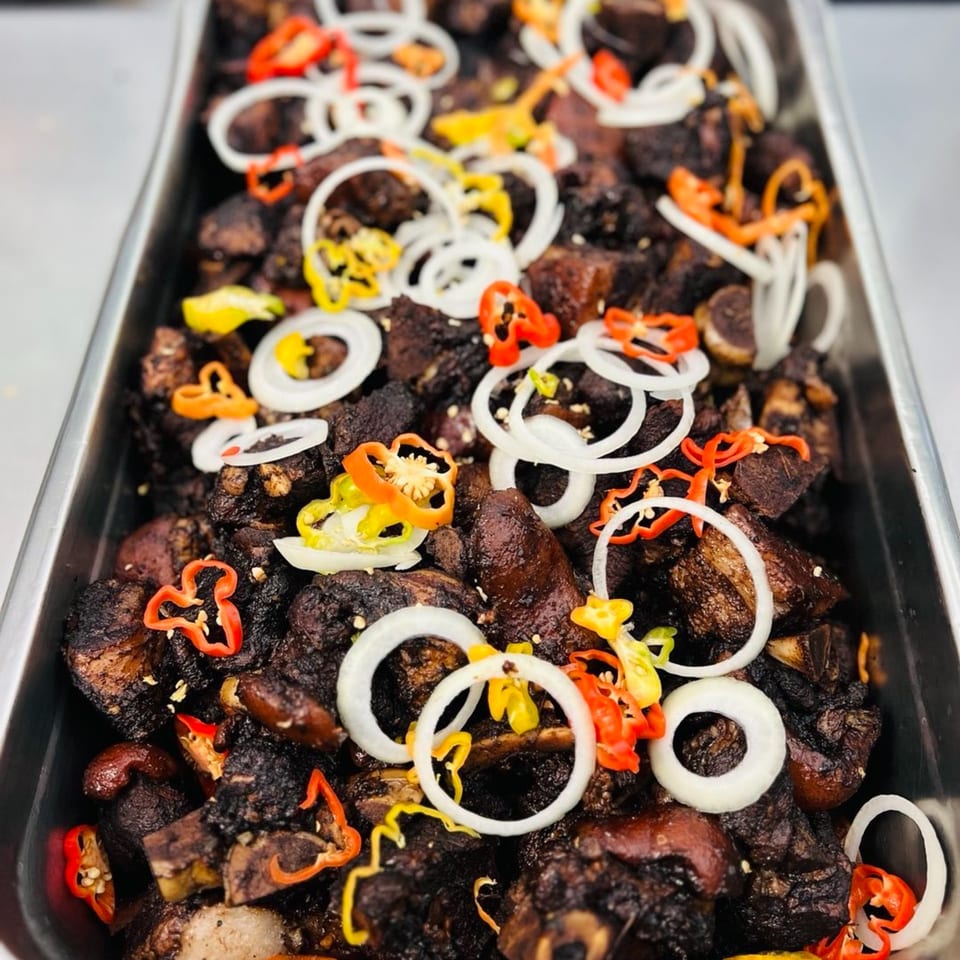 Close-up of Mr Mack's Jamaican jerk chicken, garnished with colorful bell peppers and white onion rings.